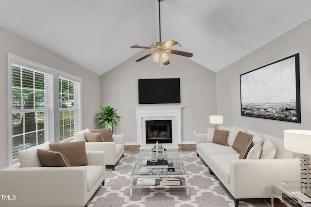 living area featuring ceiling fan, a high end fireplace, lofted ceiling, and wood finished floors