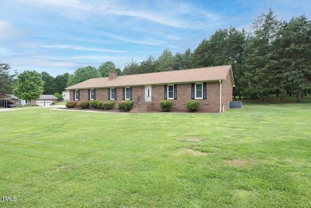 ranch-style home featuring a chimney, a front yard, brick siding, and cooling unit