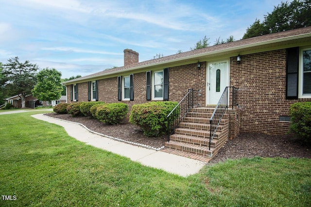 ranch-style home featuring a chimney, a front yard, and brick siding