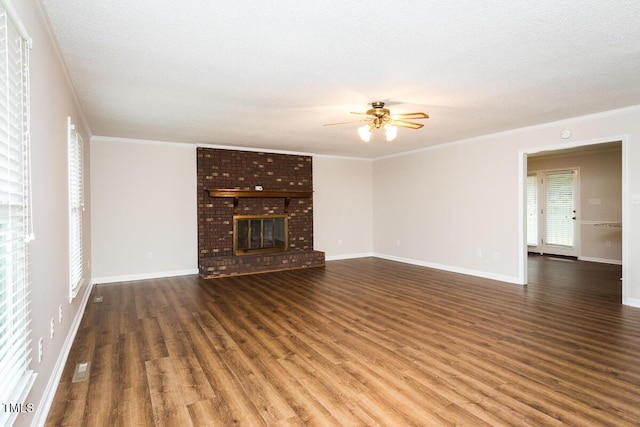 unfurnished living room with ceiling fan, crown molding, wood finished floors, a brick fireplace, and baseboards