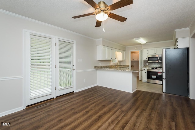 kitchen featuring appliances with stainless steel finishes, a peninsula, dark wood-type flooring, crown molding, and a textured ceiling