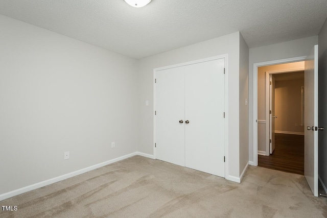 unfurnished bedroom with light colored carpet, a closet, and baseboards
