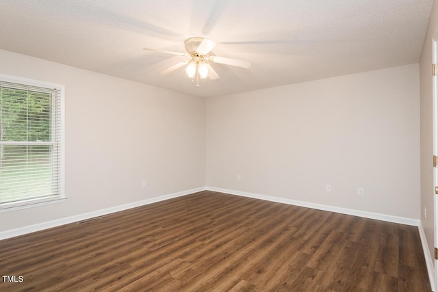 spare room featuring dark wood-style floors, ceiling fan, and baseboards