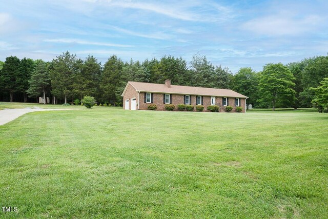 ranch-style house featuring brick siding, a chimney, and a front yard