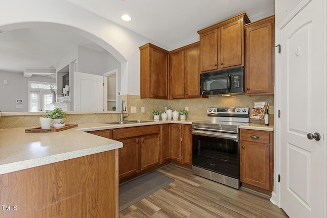 223 Morgan Brook Way, Rolesville, NC 27571 - kitchen with stainless steel electric stove, black microwave, a sink, brown cabinets, and decorative backsplash