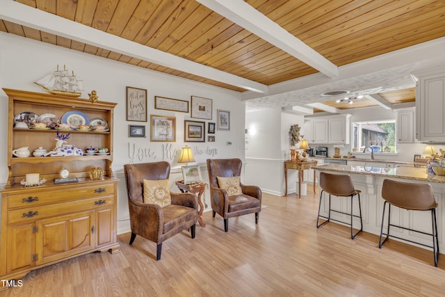 living area with light wood-type flooring, beamed ceiling, wood ceiling, and baseboards