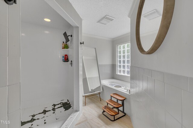 bathroom with tiled shower, ornamental molding, and a textured ceiling