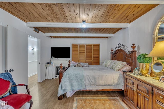 bedroom featuring beamed ceiling, light wood-style floors, and wood ceiling