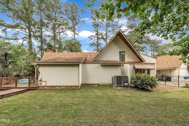 rear view of house featuring a chimney, central AC, a wooden deck, and roof with shingles