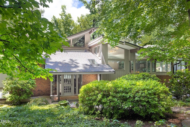 back of property featuring brick siding and a sunroom