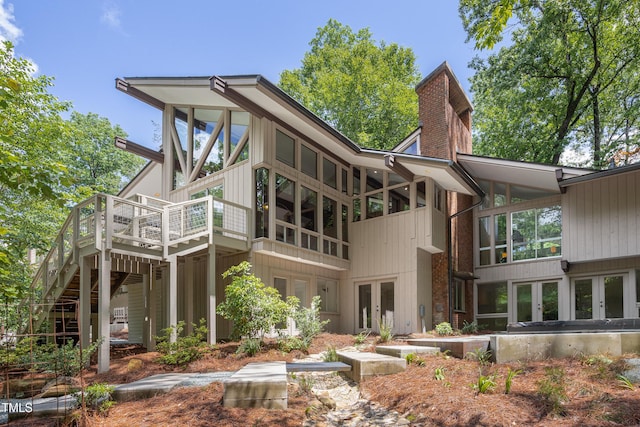 back of house with french doors, a chimney, and a wooden deck