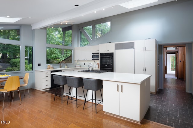 kitchen with stainless steel microwave, a skylight, dishwashing machine, a kitchen island, and light countertops