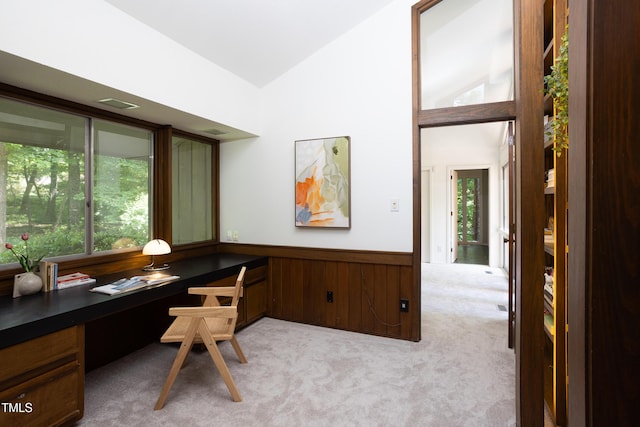 carpeted office with built in study area, vaulted ceiling, healthy amount of natural light, and wainscoting