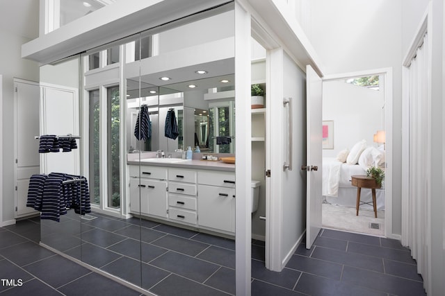 bathroom with tile patterned flooring, healthy amount of natural light, connected bathroom, vanity, and a towering ceiling