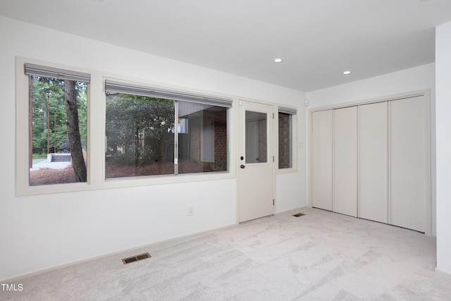 unfurnished bedroom featuring light carpet, recessed lighting, and a closet