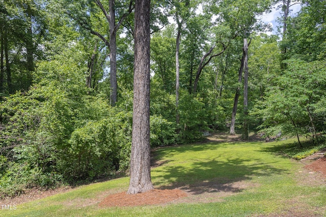 view of green lawn featuring a view of trees