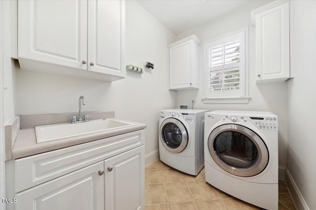 washroom featuring cabinet space, washing machine and dryer, light tile patterned floors, and baseboards