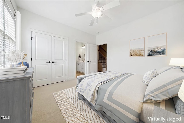 bedroom featuring light carpet, a closet, connected bathroom, and a ceiling fan
