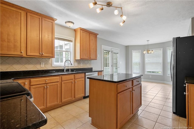 kitchen with stainless steel appliances, a sink, a center island, decorative backsplash, and a chandelier
