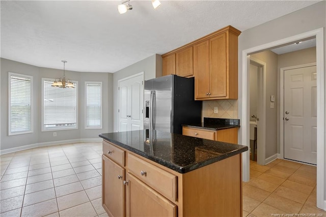 kitchen with stainless steel fridge with ice dispenser, light tile patterned flooring, a chandelier, baseboards, and decorative backsplash