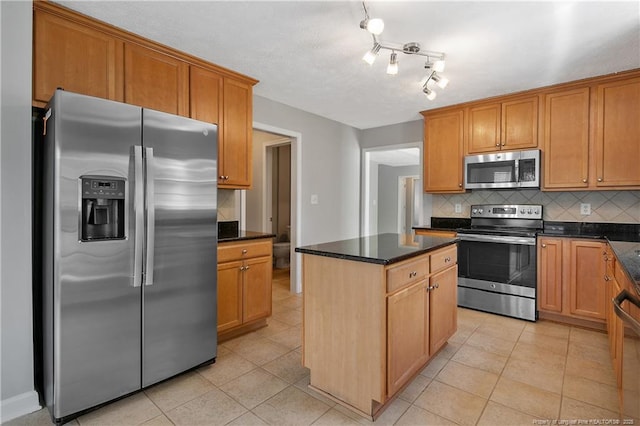 kitchen with appliances with stainless steel finishes, backsplash, a kitchen island, and light tile patterned floors