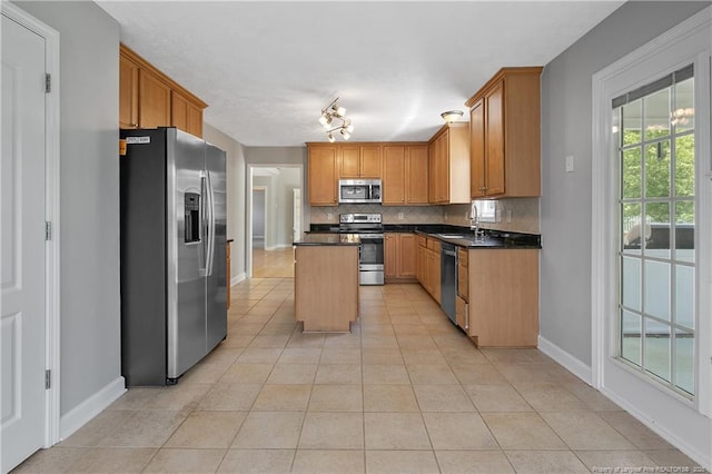kitchen featuring stainless steel appliances, decorative backsplash, light tile patterned flooring, and dark countertops