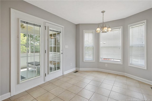 unfurnished dining area with a chandelier, baseboards, plenty of natural light, and tile patterned floors