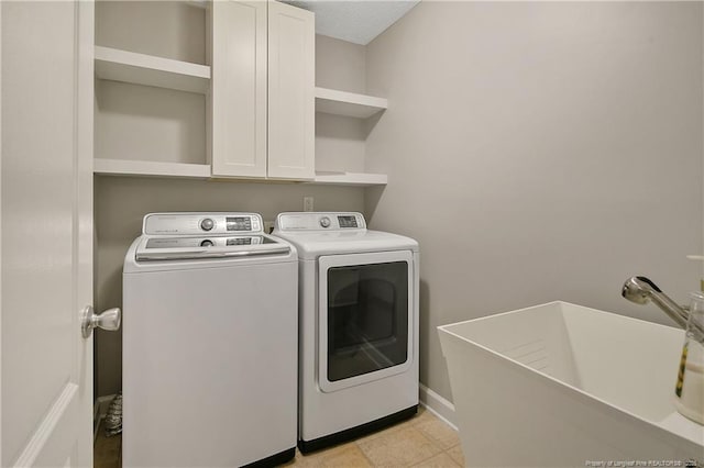 washroom with washer and dryer, cabinet space, and baseboards