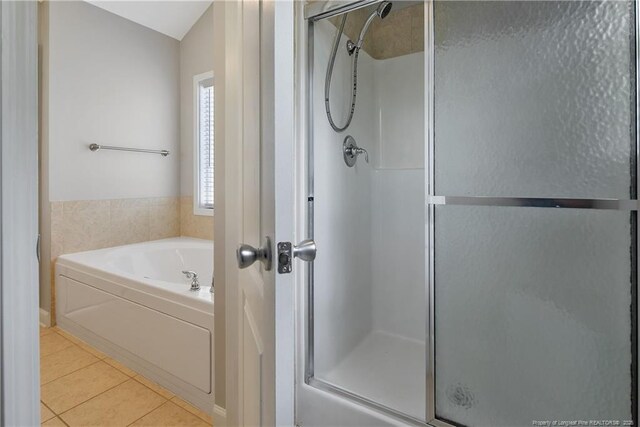bathroom with a shower stall, tile patterned flooring, and a bath