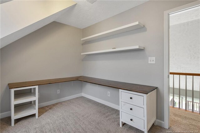 unfurnished office with light carpet, baseboards, and a textured ceiling