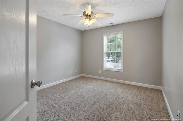 carpeted empty room featuring baseboards, ceiling fan, and a textured ceiling