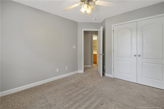 unfurnished bedroom featuring baseboards, light colored carpet, a closet, and a ceiling fan