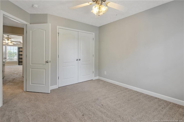unfurnished bedroom featuring carpet, baseboards, a closet, and ceiling fan