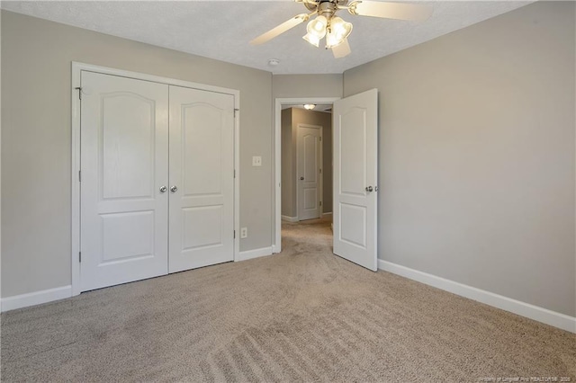 unfurnished bedroom featuring light colored carpet, baseboards, a closet, and ceiling fan