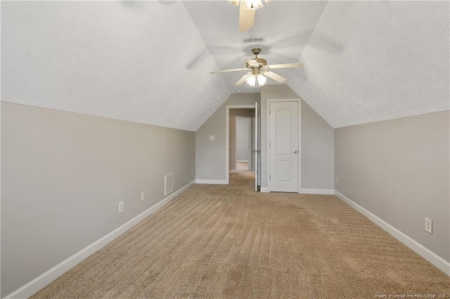 bonus room featuring a ceiling fan, a textured ceiling, carpet flooring, baseboards, and lofted ceiling