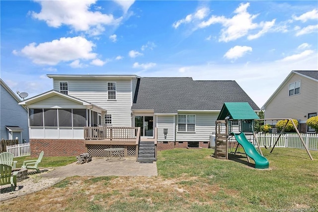 rear view of house featuring a playground, a shingled roof, a sunroom, a wooden deck, and a patio