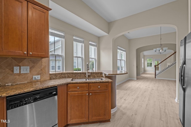 1020 Kingston Grove Dr, Cary, NC 27519 - kitchen featuring stainless steel appliances, a sink, arched walkways, and brown cabinetry