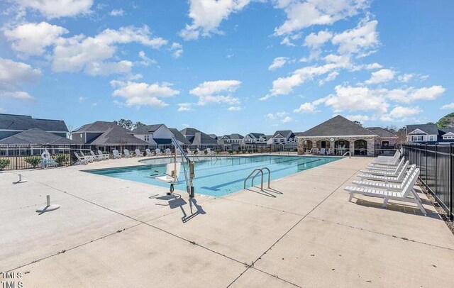 community pool featuring fence, a patio area, and a residential view