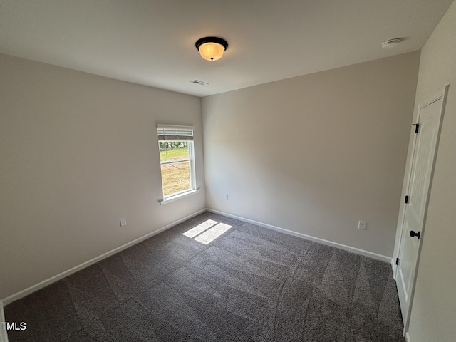spare room featuring dark colored carpet, baseboards, and a smoke detector