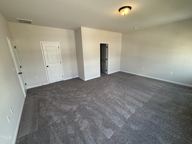 empty room with dark colored carpet and baseboards