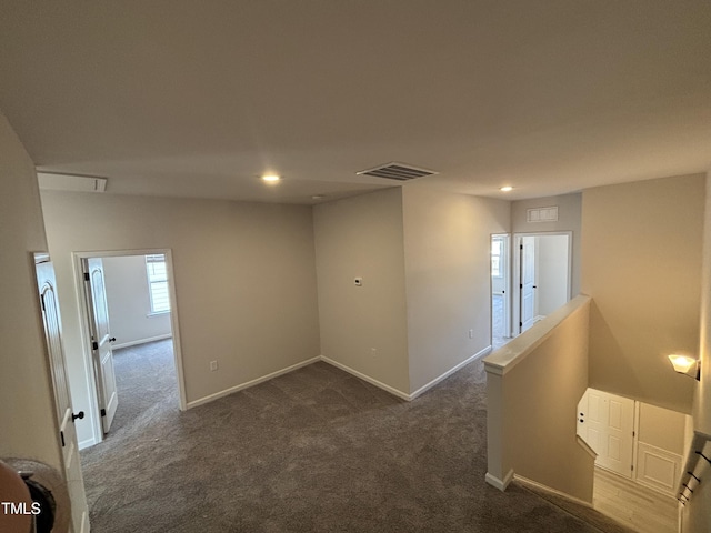empty room with dark colored carpet, recessed lighting, and baseboards