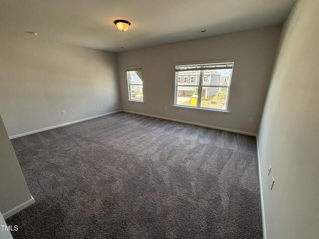 unfurnished room with dark carpet and baseboards