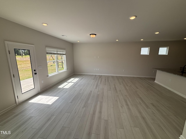 unfurnished living room with light wood-type flooring, baseboards, and recessed lighting