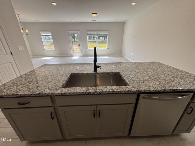 kitchen with dishwasher, a sink, open floor plan, light stone counters, and recessed lighting