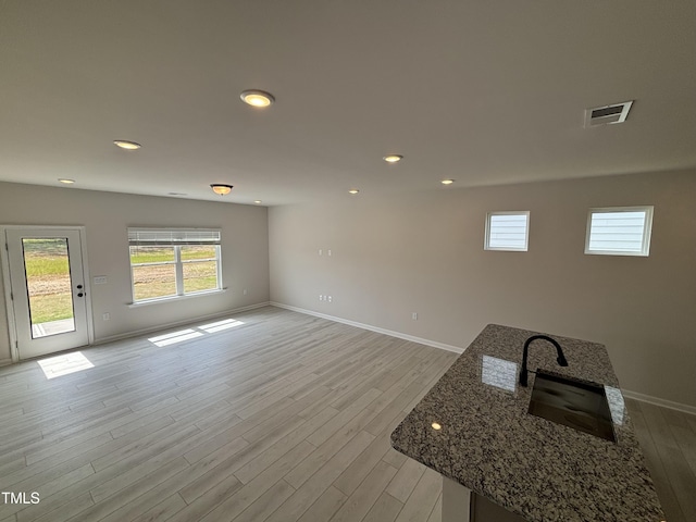unfurnished living room with healthy amount of natural light, baseboards, light wood-style floors, and recessed lighting