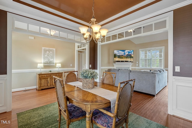182 Brendamoore Ct, Fuquay Varina, NC 27526 - dining space with a chandelier, wainscoting, wood finished floors, crown molding, and a fireplace