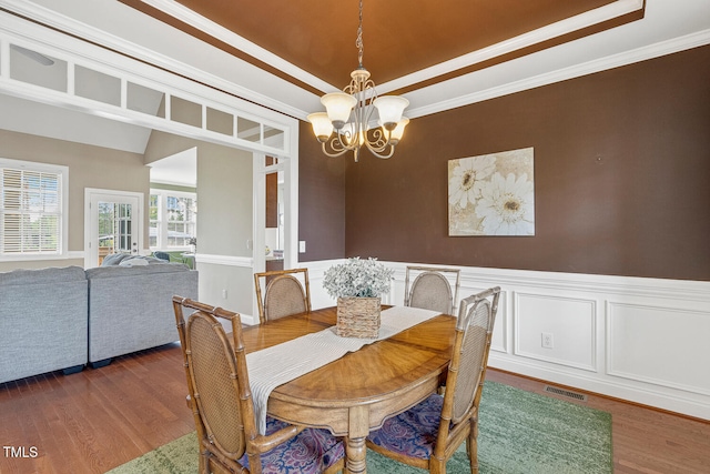 182 Brendamoore Ct, Fuquay Varina, NC 27526 - dining area featuring a chandelier, a raised ceiling, wood finished floors, wainscoting, and crown molding