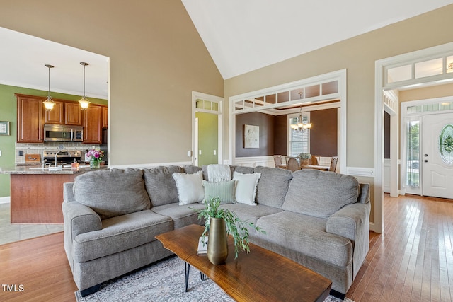 182 Brendamoore Ct, Fuquay Varina, NC 27526 - living room featuring a chandelier, high vaulted ceiling, light wood-type flooring, and a wainscoted wall