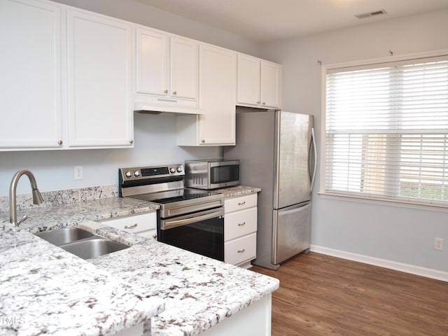 kitchen with stainless steel appliances, under cabinet range hood, white cabinets, and a sink