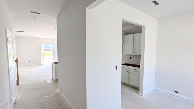 hallway featuring unfinished concrete flooring and baseboards